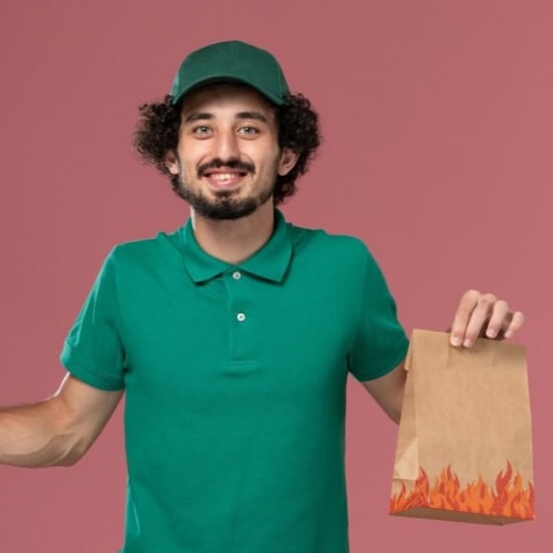 front-view-male-courier-green-uniform-cape-holding-food-package-light-pink-background-service-uniform-delivery_140725-39343-min