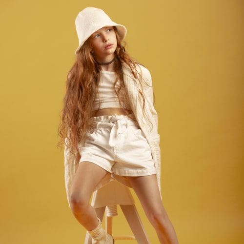 full-shot-girl-posing-chair-with-hat-min