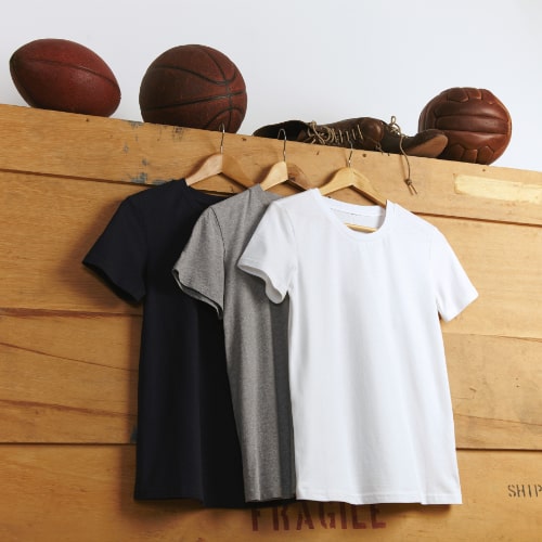 presentation-white-gray-black-plain-shortsleeve-t-shirts-with-vintage-football-basketball-volleyball-old-sports-leather-boots-top-wooden-shipping-box-min